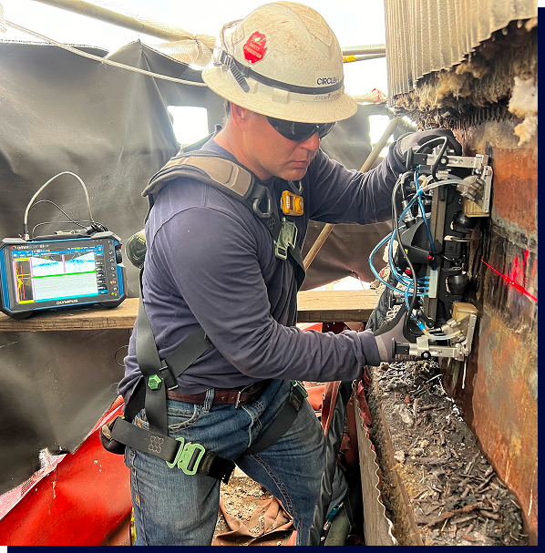 A man with a hard hat and safety glasses operates machinery, demonstrating safety and focus in his work environment.